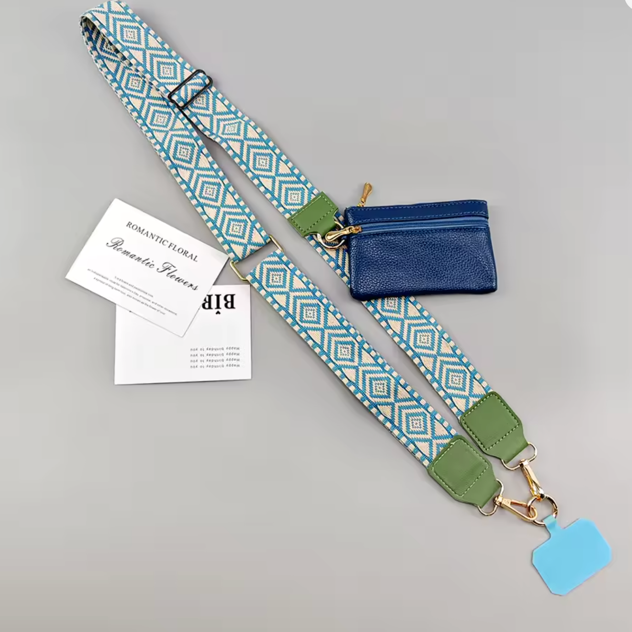 A shoulder strap bag set with a blue and white geometric patterned strap, olive green leather accents, a small blue zippered pouch, and printed cards on a light gray background.