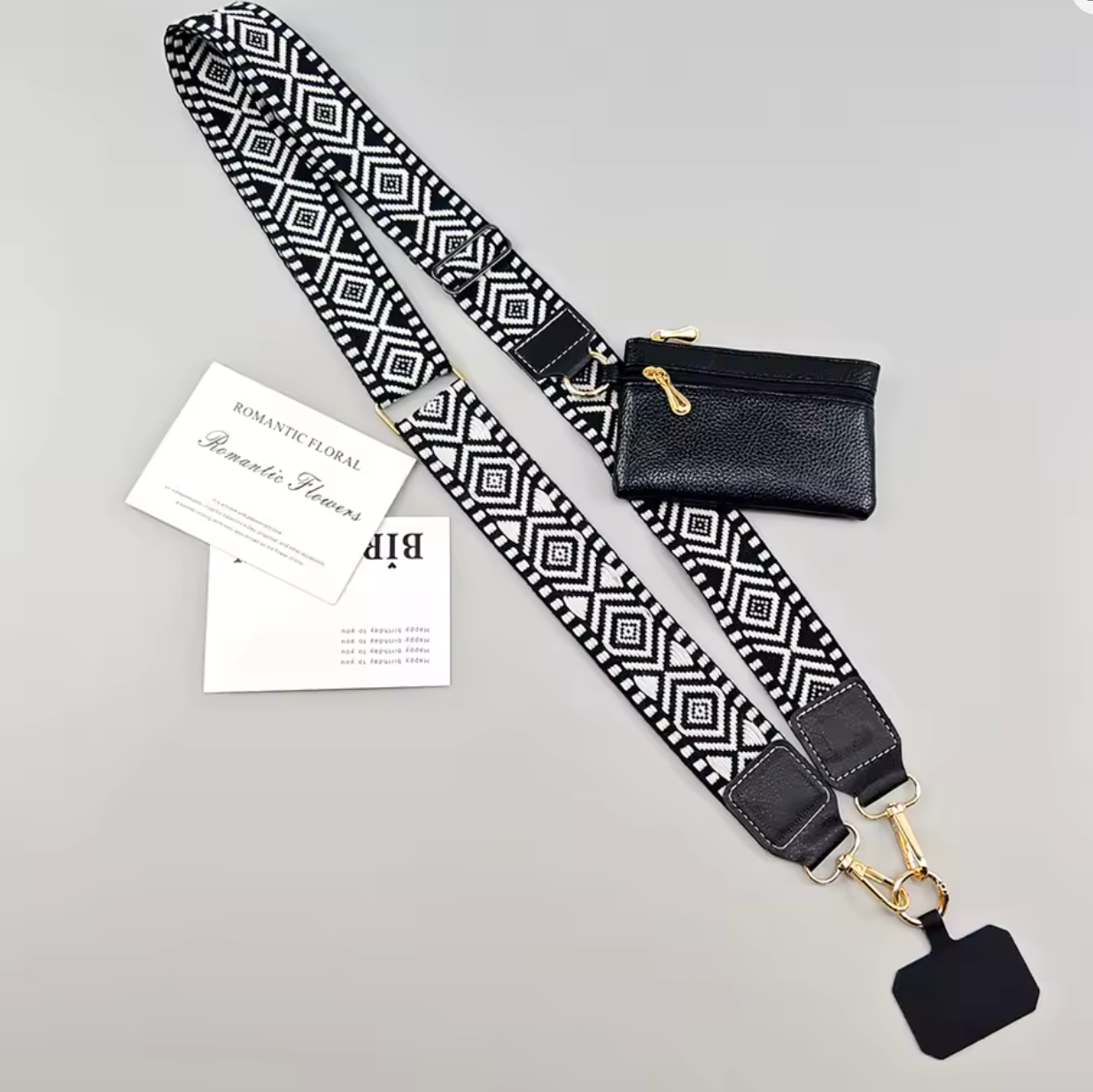 A black and white geometric patterned shoulder strap with gold-tone hardware, shown laid out on a light gray background alongside a small black pouch, two branded cards, and a blank black tag. The brand name 'Bip' is visible on the cards.