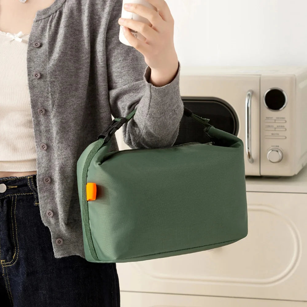 Person holding a green bag with an orange tag in front of a washing machine.