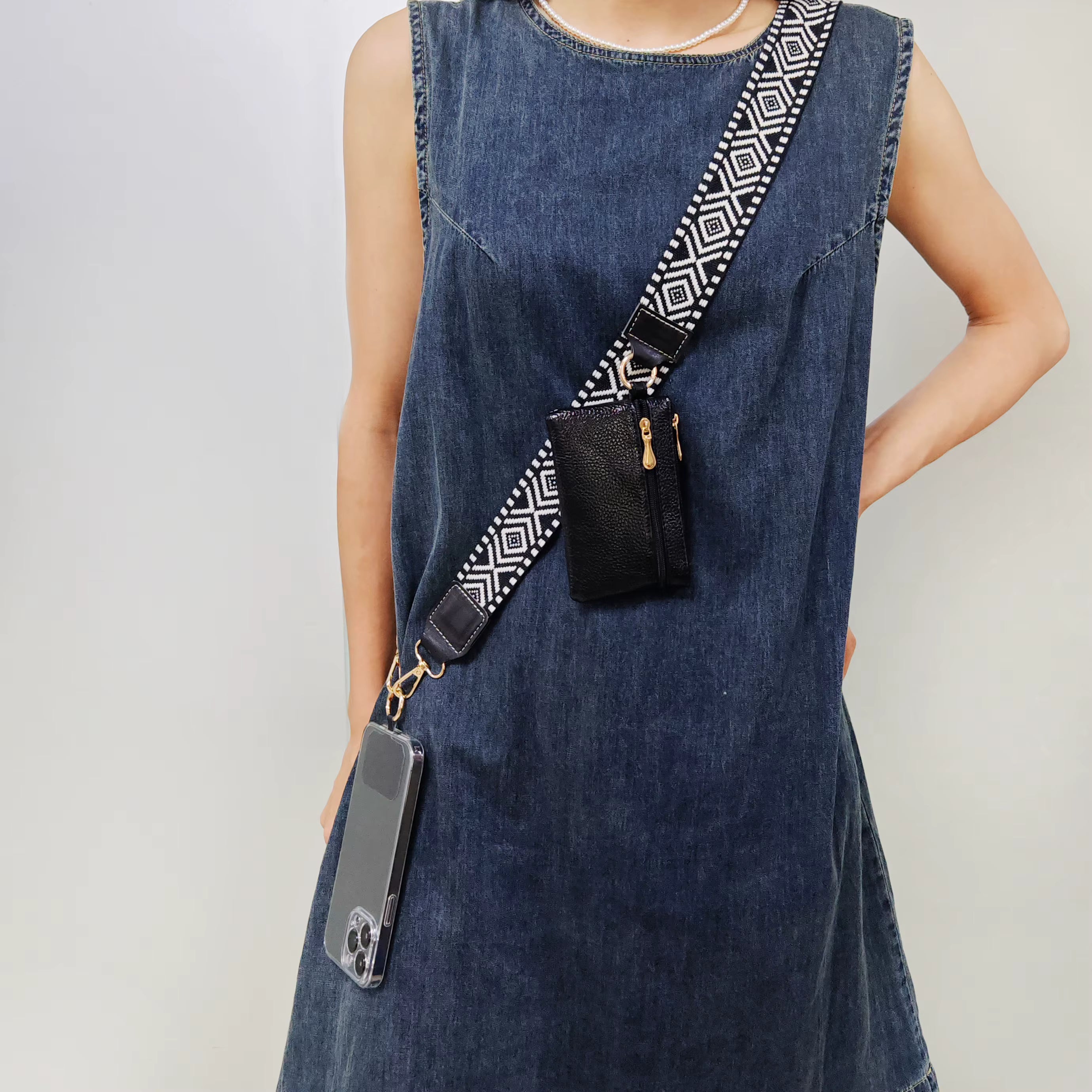 Person wearing a denim dress with a black crossbody bag featuring a geometric strap.