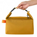 Yellow pouch with an orange tag held by a hand on a white background