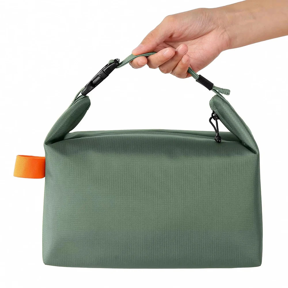 Green toiletry bag with orange tag held by a hand on a white background